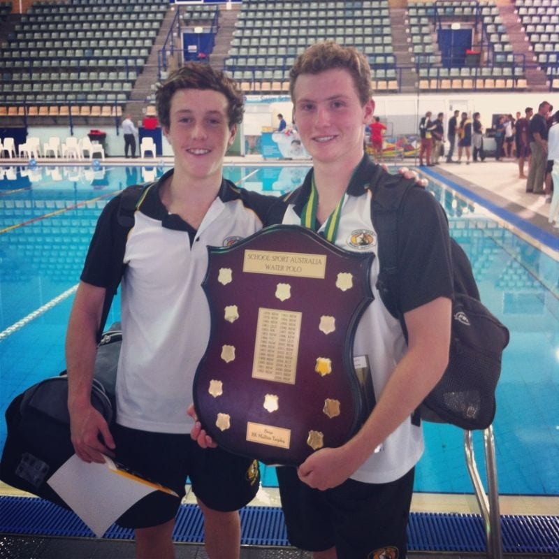 Alex and a teammate holding the School Sport Australia water polo shield on the pool deck