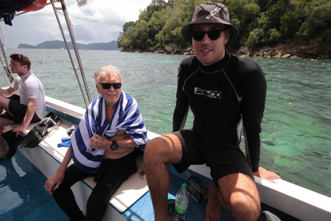My grandfather wrapped in a striped towel on a dive boat, with me beside him in a wetsuit