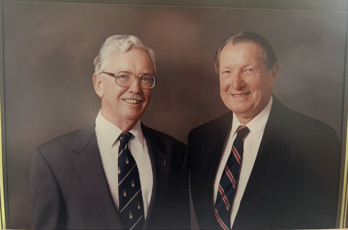 Formal studio portrait of two older men in suits and ties